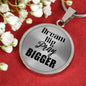 Polished surgical steel Dream Big Pray Bigger necklace on red background.